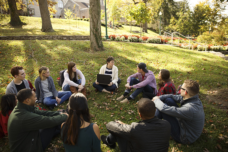 A class sits in a circle on the grass.