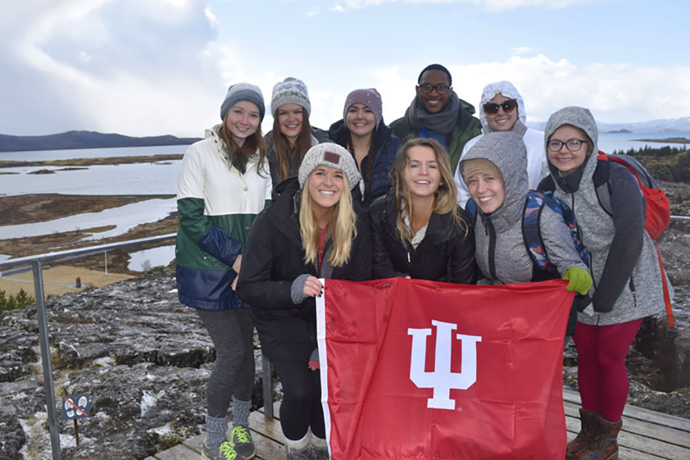Students wearing winter clothes hold up an IU flag.